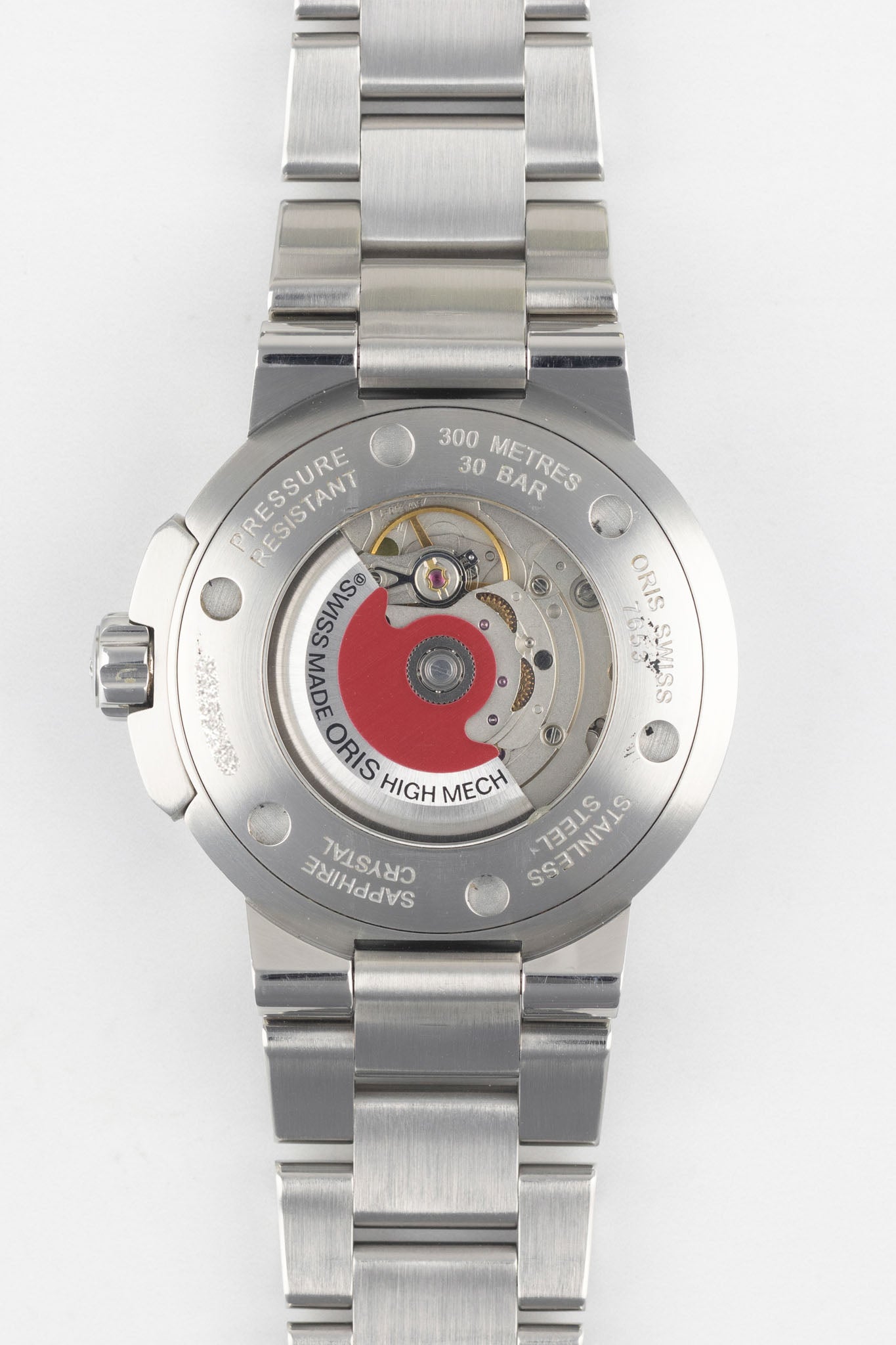 A clear, direct shot of the exhibition case back of an Oris Aquis Date, revealing the automatic mechanical movement and the iconic red Oris rotor.