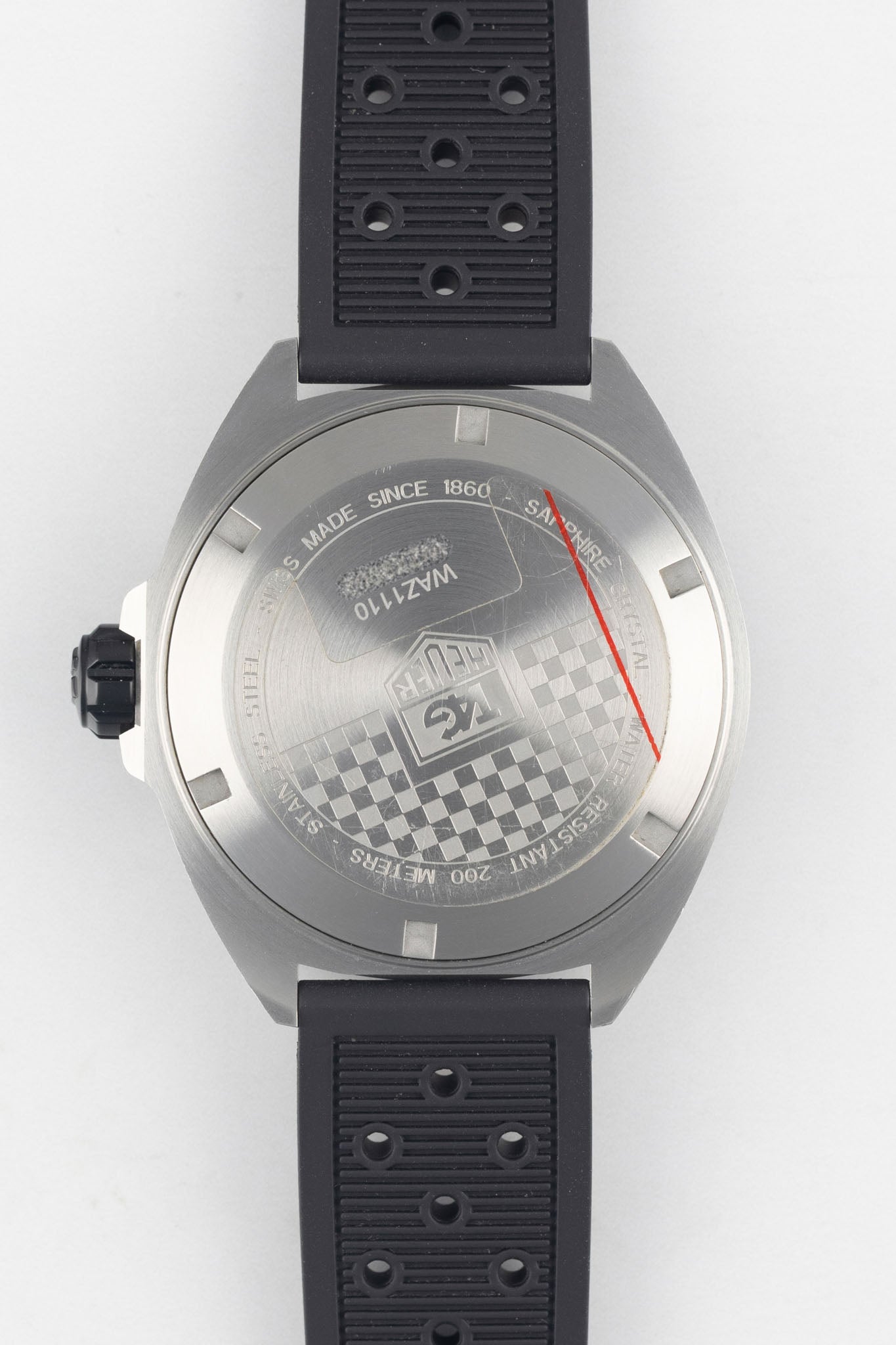 A direct shot of the stainless steel screw-down case back, featuring an engraved checkered flag pattern, the TAG Heuer logo, and technical specifications like "200 Meters Water Resistant."
