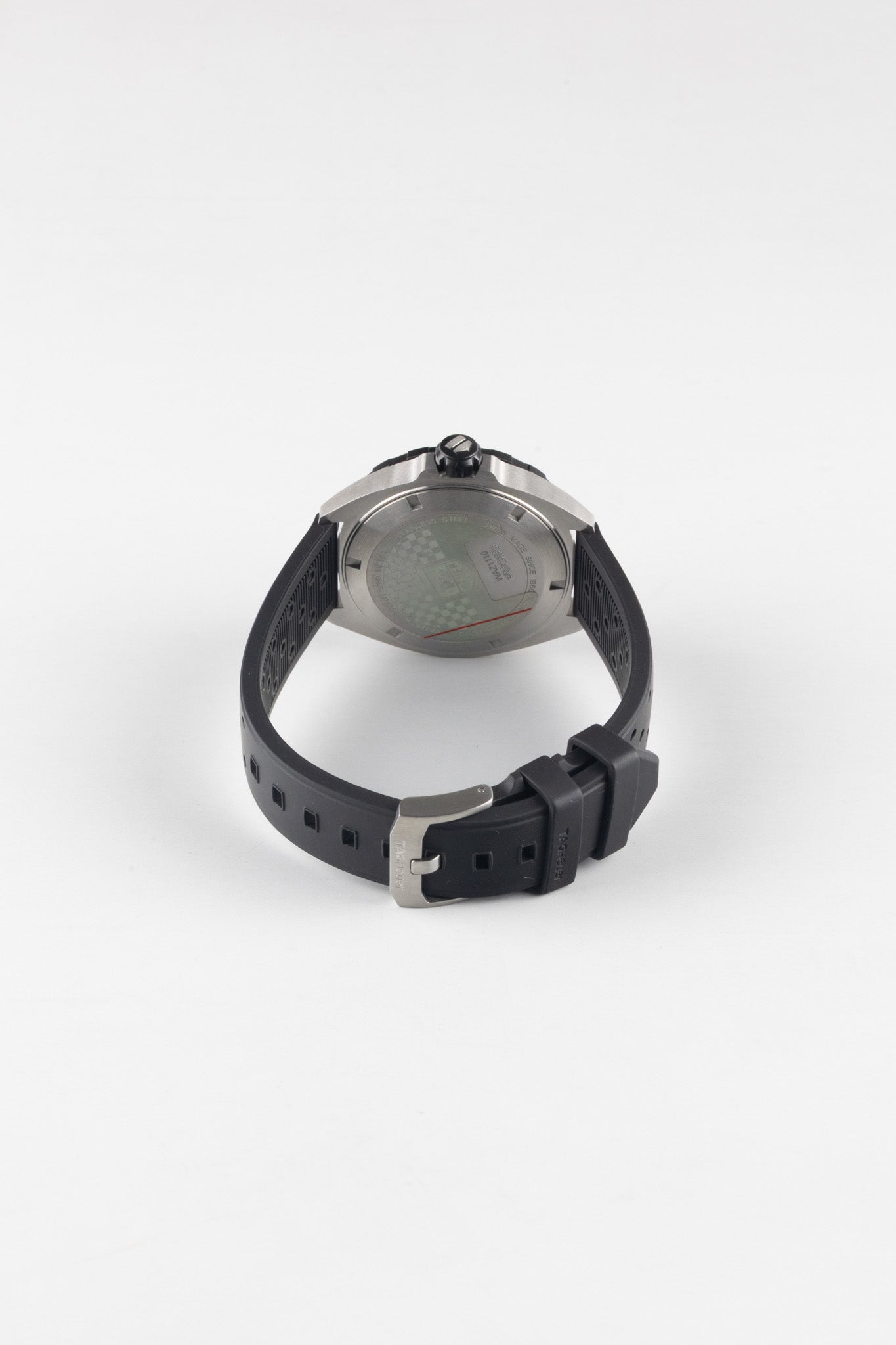 A rear-angled view of the watch showing the underside of the black rubber strap and the stainless steel pin buckle engraved with "TAG Heuer."