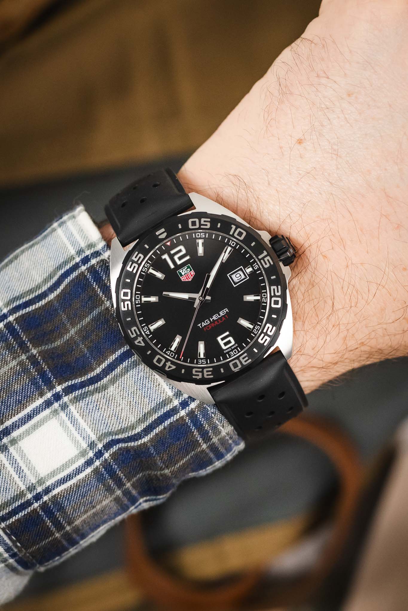 A lifestyle image of the watch being worn on a wrist, paired with a blue and white plaid shirt, highlighting how the watch sits against the arm.